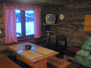 Ahkun Tupa في Lemmenjoki: غرفة مع طاولة وتلفزيون في كابينة