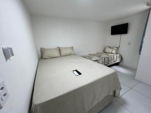 a white room with a bed and a television at Flats Brisa Antunes in Maragogi