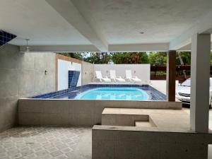 een zwembad met witte stoelen en een auto bij Flats Brisa Antunes in Maragogi