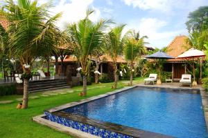 a swimming pool in a yard with palm trees at Nauna Villa Bali in Ubud