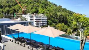 une piscine avec parasols et chaises à côté d'un bâtiment dans l'établissement Cute Studio in Aristo Beach condo - 7 min walk to Surin Beach, à Surin Beach