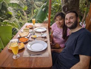 un uomo e una donna seduti a un tavolo con del cibo di Antara Green Cottage Ella a Ella Altre 9 foto