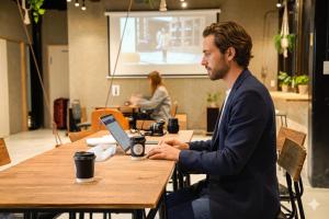 a man sitting at a table with a laptop at 富士Base御殿場 Station-Side Hideout in Gotemba