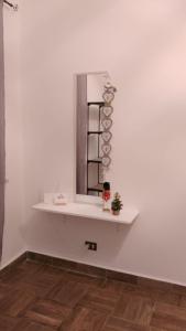 une étagère sur un mur blanc avec un miroir dans l'établissement Montereale holiday house, à Monreale
