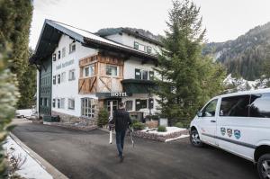 een man loopt met een busje voor een hotel bij Alpstay - Chalet Hotel Hartmann - Adults Only in Ortisei