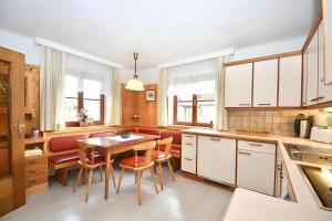 a kitchen with white cabinets and a table and chairs at Ferienhaus Sinning in Leogang