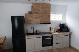 a kitchen with a black refrigerator and white cabinets at Liziera Cabin Malaia in Malaia +18 photos