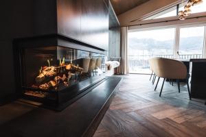 a fireplace in a living room with chairs and a table at Alpine Boutique Hotel wollée - 4 Star Superior in Schladming