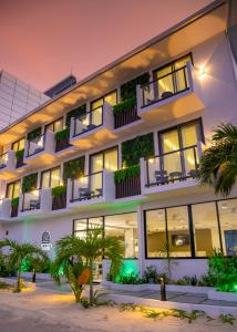 een groot wit gebouw met ramen en planten bij Sunwave Dhigurah in Dhigurah