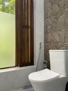 een badkamer met een wit toilet en een raam bij Sigiriya Hotel and Resort in Sigiriya