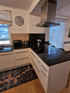 a kitchen with black counter tops and a clock on the wall at Ferienwohnung Claudia Alt-Ossiach in Altossiach