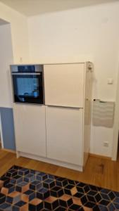 a kitchen with white cabinets and a microwave at Ferienwohnung Claudia Alt-Ossiach in Altossiach +9 photos