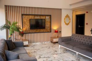 a living room with couches and a television on a wall at Airport Corner Hotel in Trabzon