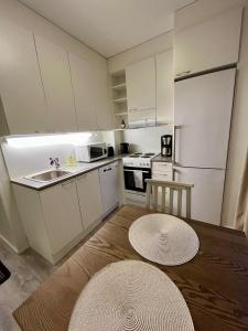 a kitchen with white cabinets and a wooden table at Modern studio apartment with free parking in Kuopio