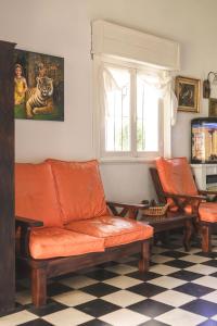 een oranje bank en 2 stoelen in de woonkamer bij Casa Ganesha Chapadmalal in Chapadmalal