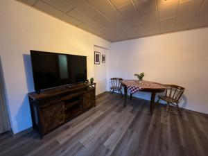 a living room with a table and a flat screen tv at Hotel Mühlental in Wernigerode