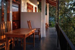 a wooden table and chairs on the porch of a house at Amado Homestay Ella in Ella