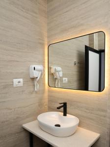 een badkamer met een wastafel en een spiegel bij Kremelo Hotel in Berat