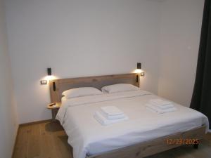 una camera da letto con un letto bianco con due asciugamani sopra di Residence ai fiori - Simone Apartment ad Arta Terme
