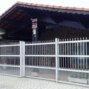 a white picket fence in front of a building at Hostelval Cantinho praia do sossego in Praia Grande +5 photos