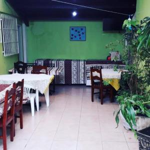 a restaurant with tables and chairs and a green wall at Hostelval Cantinho praia do sossego in Praia Grande