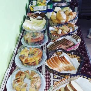 a table full of different types of pastries on plates at Hostelval Cantinho praia do sossego in Praia Grande