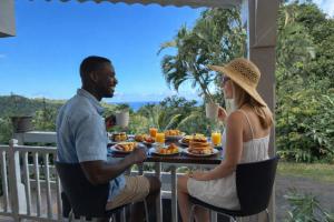 a man and a woman sitting at a table with food at Studio La Marguerite - Vue mer avec terrasse privée - calme tropical à Deshaies in Deshaies