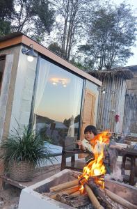 Een jong kind kookt boven een vuur. bij บ้านนอร์ดบล็อกเวนิสบ้านเวร in Ban Khun Nam Nan