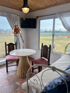 een kamer met een tafel, stoelen en een raam bij Epona in Marcos Paz