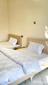 twee bedden naast elkaar in een kamer bij فندق وادي السحتن in Al Ambaḩ