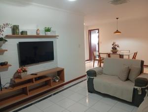 a living room with a couch and a flat screen tv at Lindo apartamento frente mar Peracanga in Guarapari