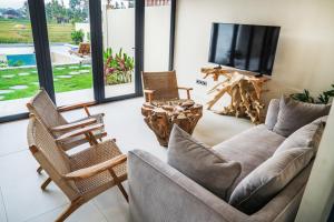 ein Wohnzimmer mit Sofa, Sesseln und Fernseher in der Unterkunft 2BDR Villa Aurelia - Construction nearby in Bedahulu
