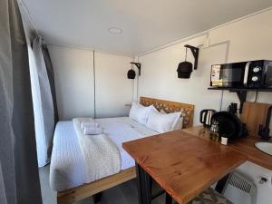 een kleine kamer met een bed en een houten tafel bij Nomade Balmaceda in Coihaique
