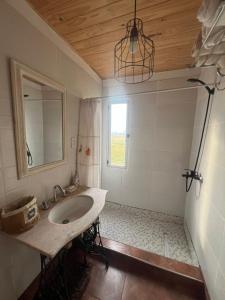 een badkamer met een wastafel, een spiegel en een raam bij Epona in Marcos Paz