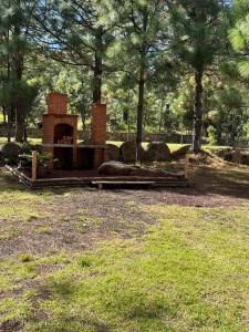 een bakstenen open haard in een park met bomen en gras bij Del Cortes Cabañas in Velasco