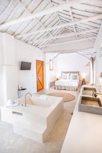 een witte kamer met een groot bad en een bed bij Cortijo de la Seda in Granada
