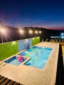 une piscine avec un flamant rose dans l'eau la nuit dans l'établissement Sabas Tent & Cottages, à Mahabaleshwar