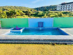 a large swimming pool with a blue and green wall at ARANYAM By StarGlaze Retreat in Mahabaleshwar