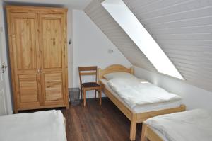 een zolderslaapkamer met twee bedden en een stoel bij Schäferstübchen - Urlaub auf dem Bauernhof in Braunsberg