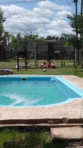 Ein Swimmingpool in einem Garten, in dem Menschen auf dem Rasen liegen. in der Unterkunft Cabaña La Florencia Domselaar in Domselaar