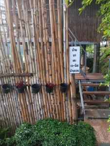 een bamboehek met potplanten en een bord bij บ้านนอร์ดบล็อกเวนิสบ้านเวร in Ban Khun Nam Nan
