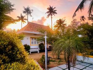 ein Haus mit Palmen vor einem Sonnenuntergang in der Unterkunft CASA DE CANOLI - A Private backwater villa in Kodungallūr