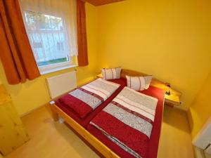een kleine gele kamer met een bed met rood-witte dekens bij Ferienwohnung Landmannsruh in Lubmin
