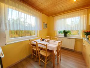een eetkamer met een tafel en twee ramen bij Ferienwohnung Landmannsruh in Lubmin