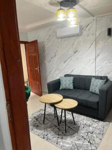 een woonkamer met een bank en twee tafels bij Résidence Azur in Libreville