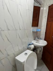 een witte badkamer met een toilet en een wastafel bij Résidence Azur in Libreville