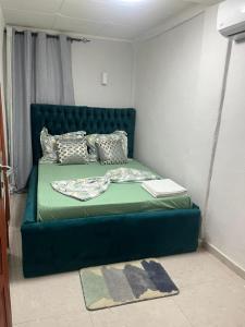 een groen bed met kussens en een boek erop bij Résidence Azur in Libreville