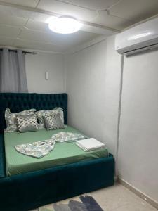 een bed in een kamer met een groene bank bij Résidence Azur in Libreville +5 foto's