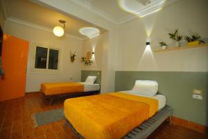 a room with two beds with orange and white sheets at Jme Bunks Hostel in Aswān