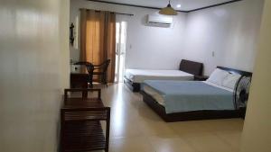 a hotel room with two beds and a table at Shine Hotel in Sampong +2 photos
